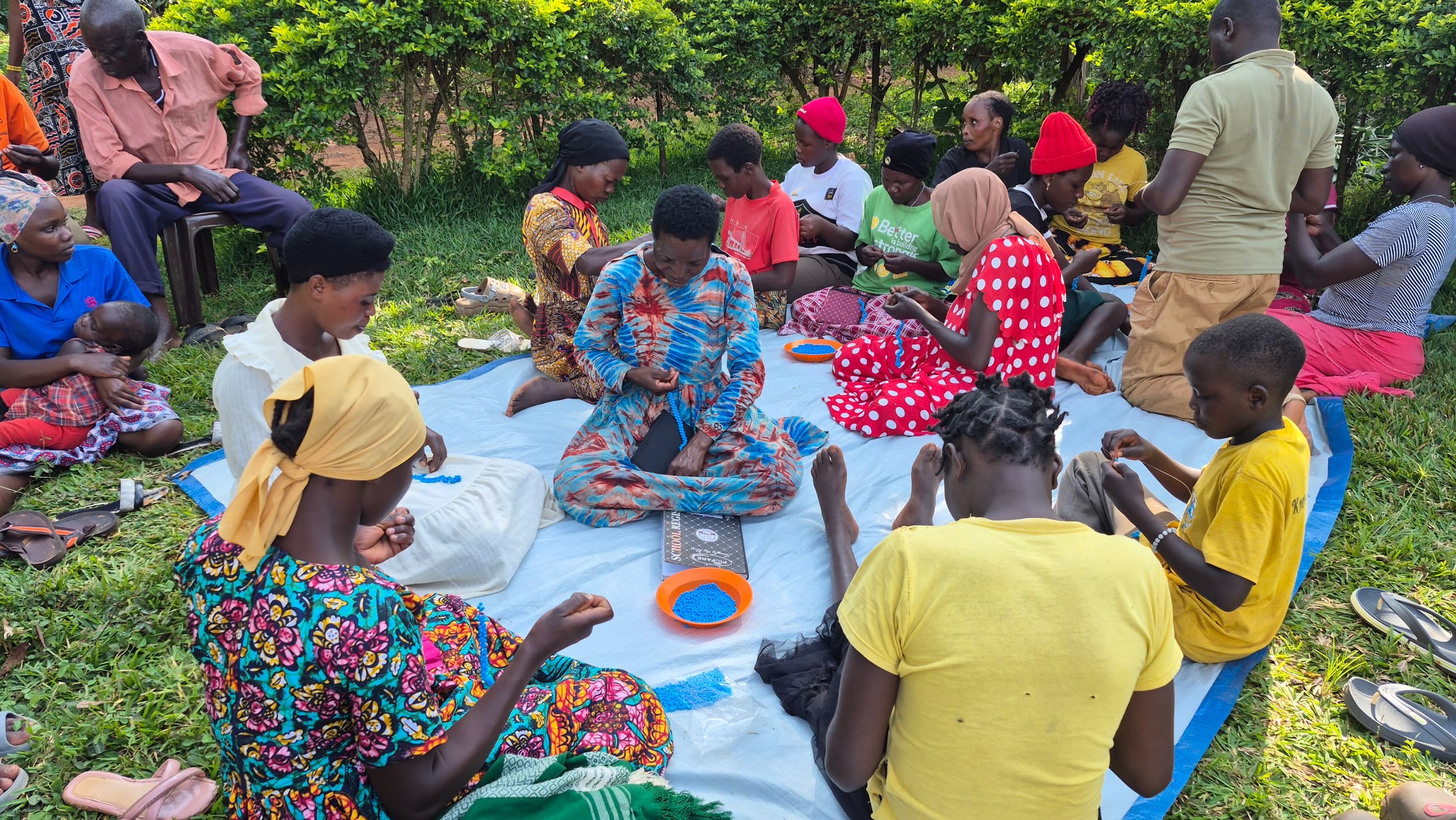 Women gathered outdoors while learning beading and vocational skills in Uganda.